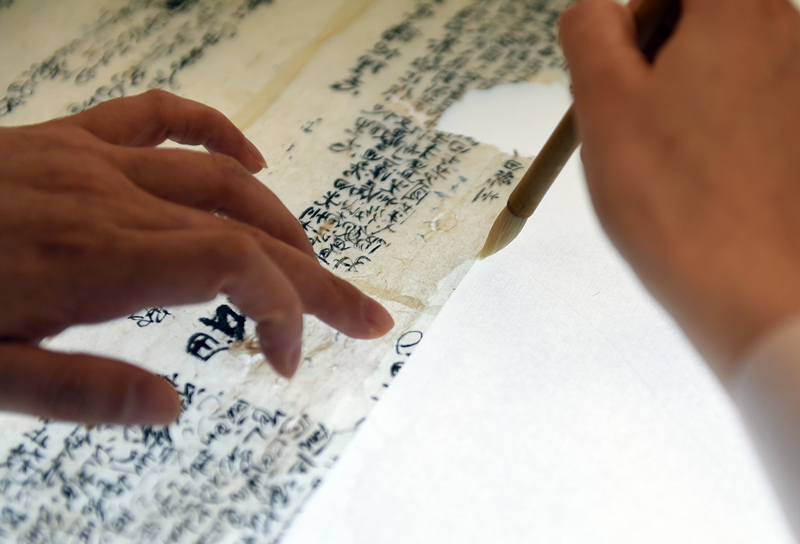 2022年5月17日，在安徽博物院文物科技保护中心纸质文物修复室，工作人员对古籍文物进行补全。